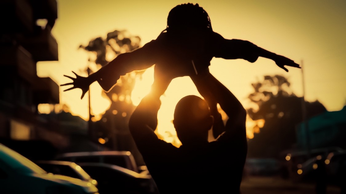 Silhouette of man lifting child